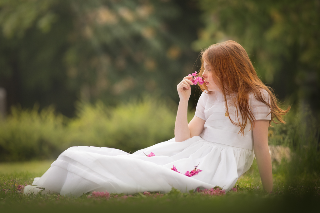 foto de niña pelirroja en vestido blanco el día de su reportaje de primera comunión en exteriores en campo de flores