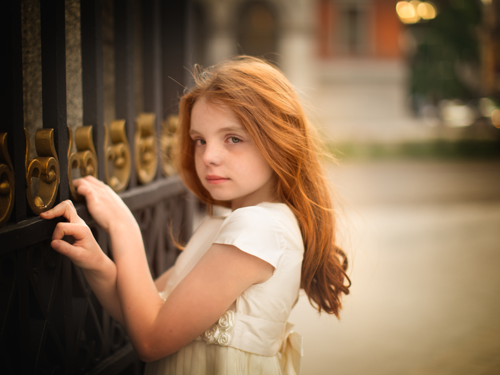 foto de niña pelirroja en vestido blanco el día de su reportaje de primera comunión en exteriores