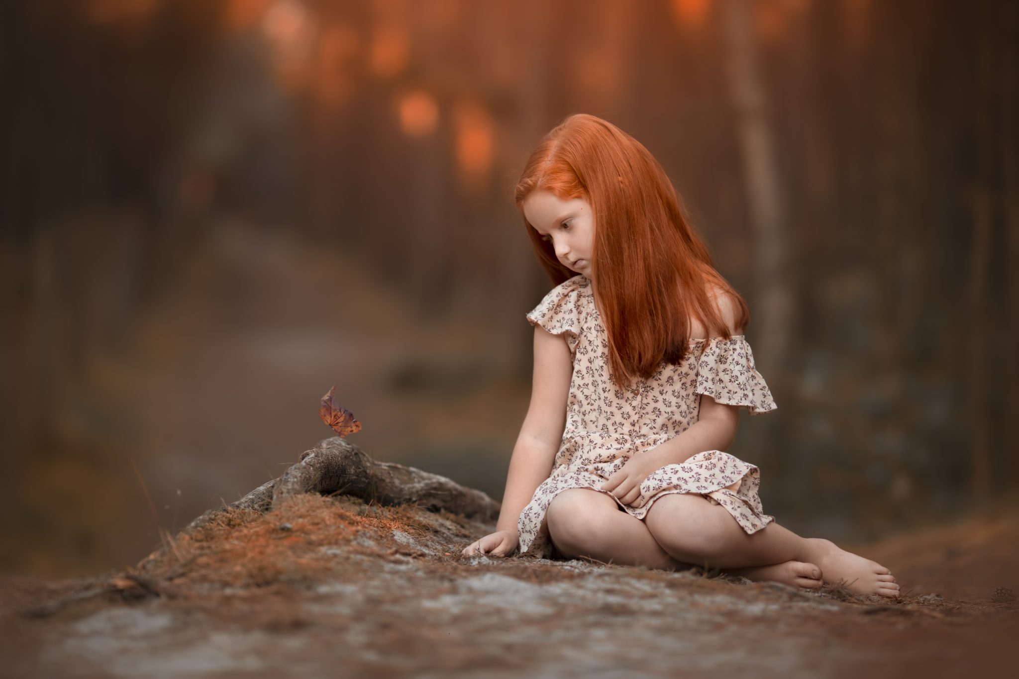 una foto de niña pelirroja en exteriores al atardecer con una hoja