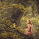 una foto de niña rubia con pelo largo sentada en un árbol