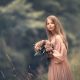 una foto de niña rubia con pelo largo y ramo de flores y vestido rosa en el campo en reportaje fotográfico pre comunión