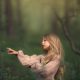 una foto artistica de niña rubia con pelo largo y vestido rosa en un bosque