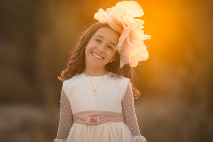 una niña feliz en su vestido blanco de encaje el dia de su primera comunión