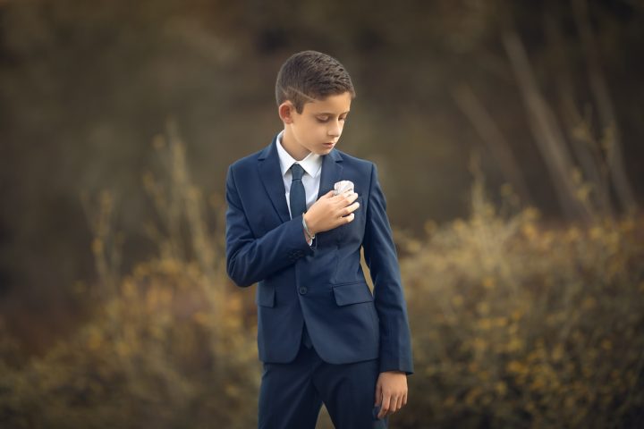 un varon en traje de primera comunión en una sesion fotografica en exteriores