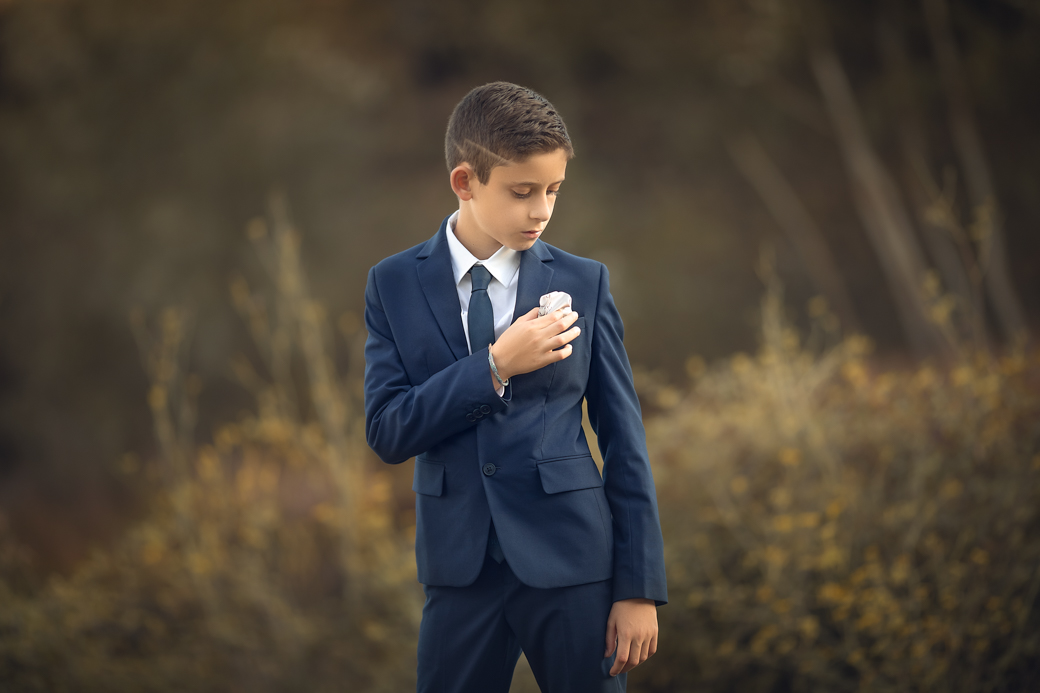 un varon en traje de primera comunión en una sesion fotografica en exteriores