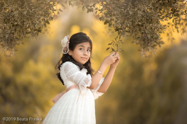 una foto de niña en vestido de primera comunión jugando en exteriores