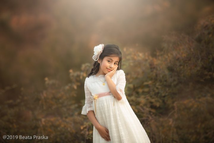 una foto tierna de una ninia en vestido de primera comunión en exteriores